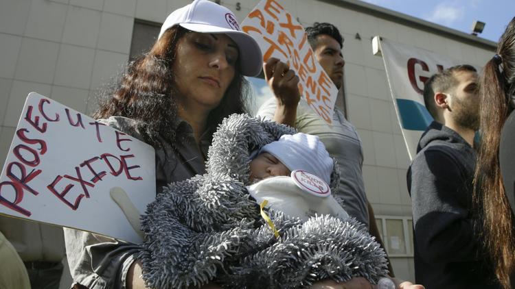 Person holding child at protest against Exide battery recycling factory near Los Angeles, CA.